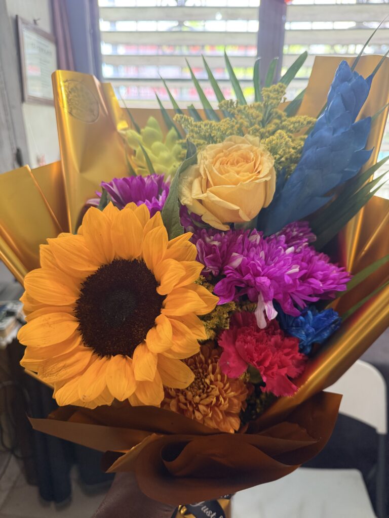 Colorful bouquet featuring sunflowers, orange and purple flowersery